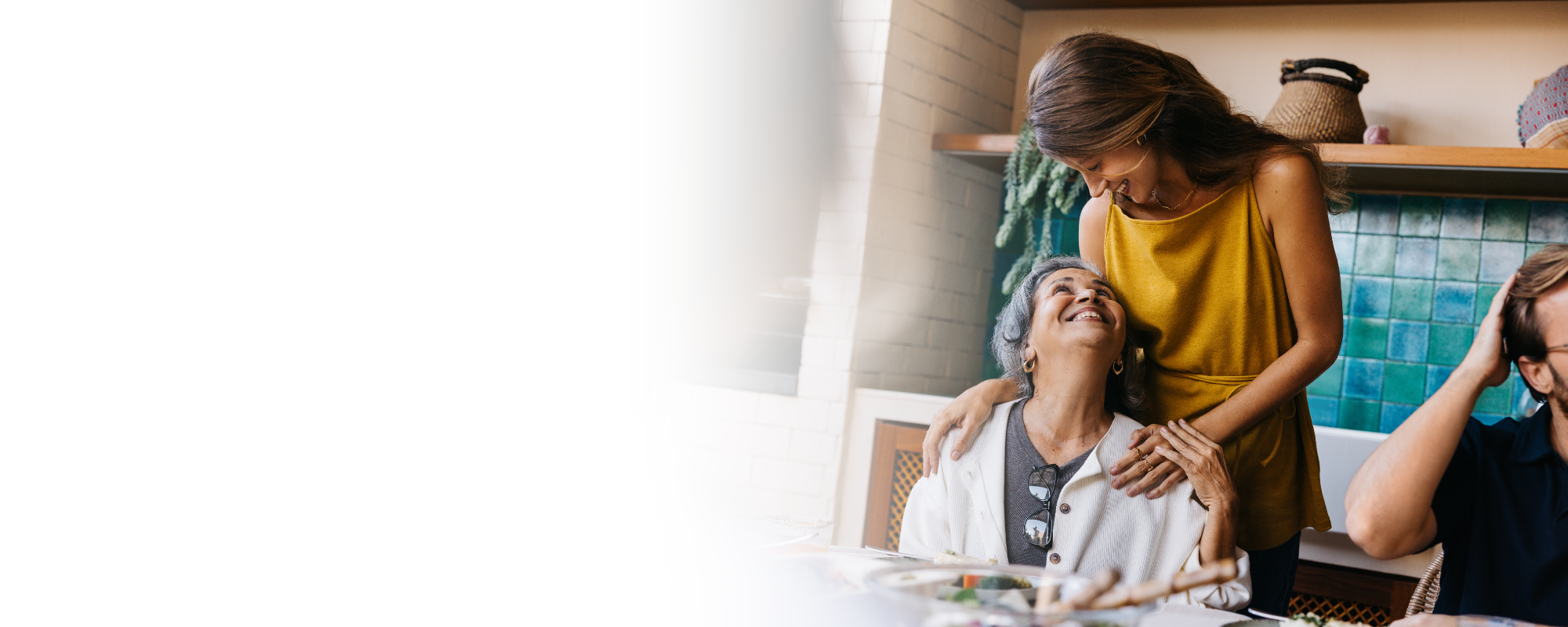 Caregiver embracing senior woman at family dinner table – Home Care in Highland County, OH Caregiver embracing senior woman at family dinner table - Home Care in Highland County, OH